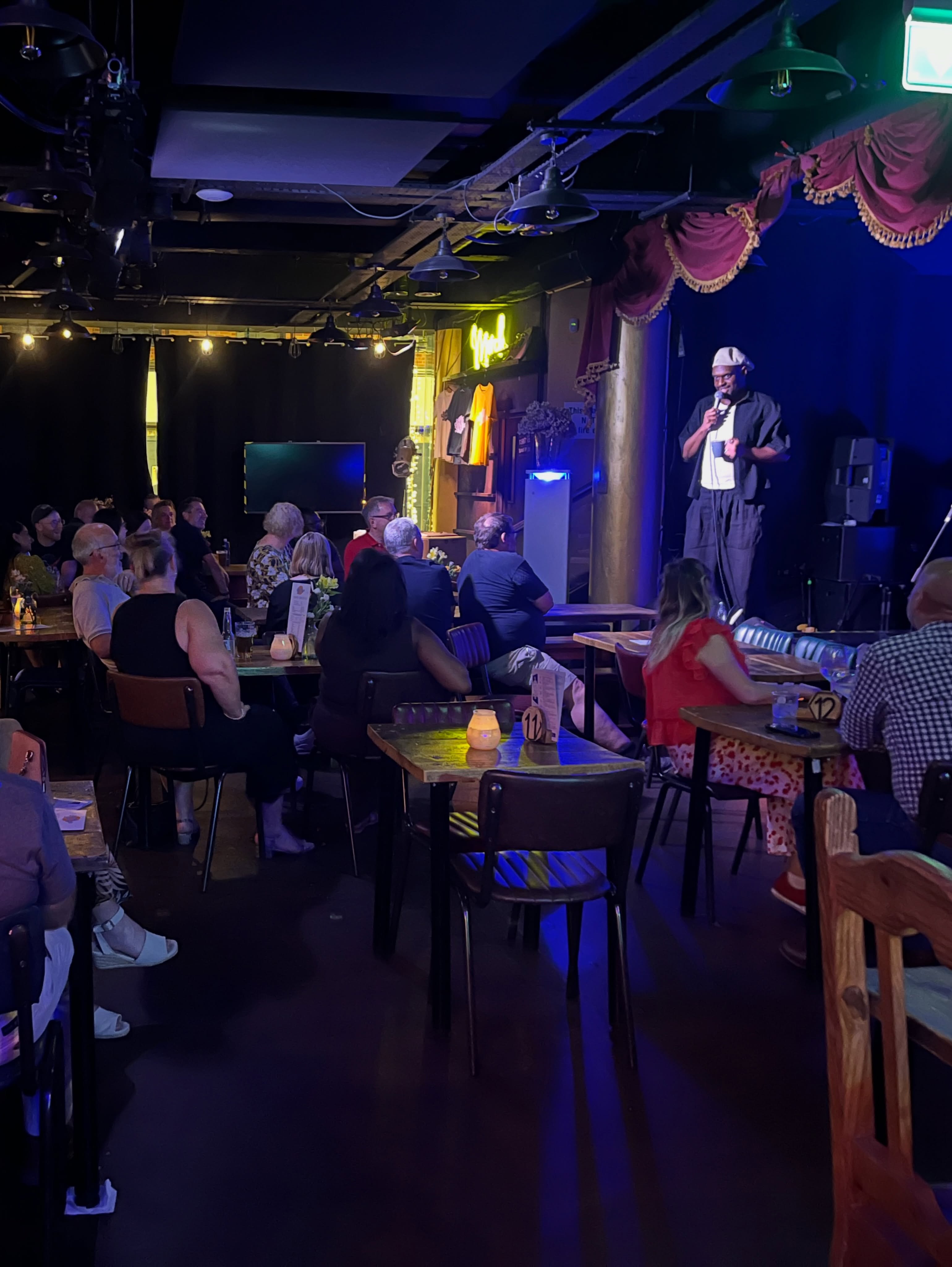 A comedian performing to a full audience at The Sound Lounge