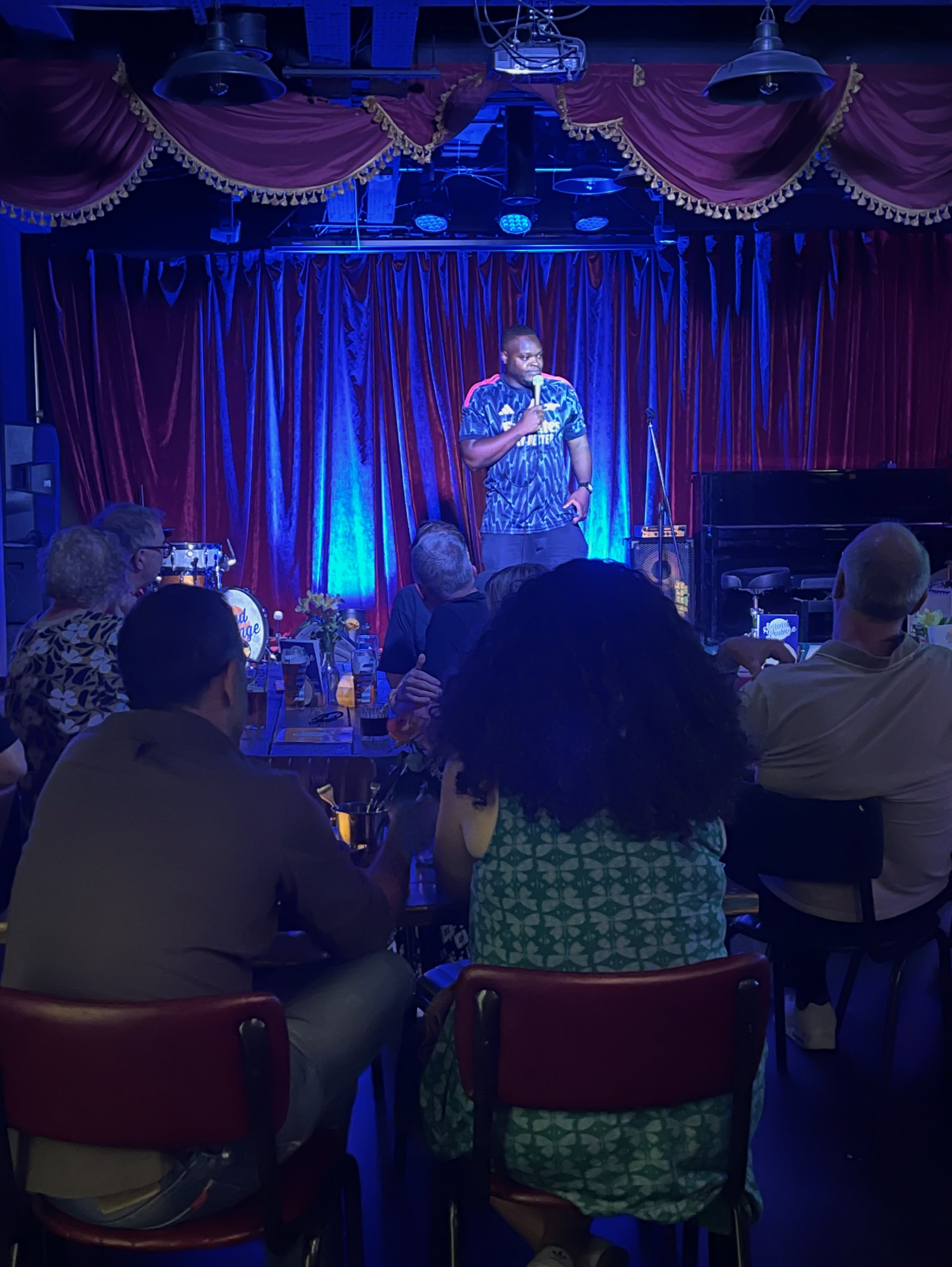 A comedian performing beneath the lights at The Sound Lounge